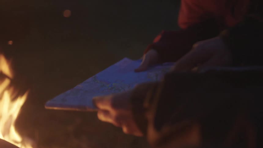 People looking at a map next to a fire outdoors