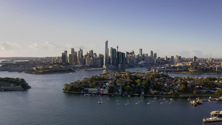 Ships sit at dock near peninsula crowded with buildings that sits across city downtown