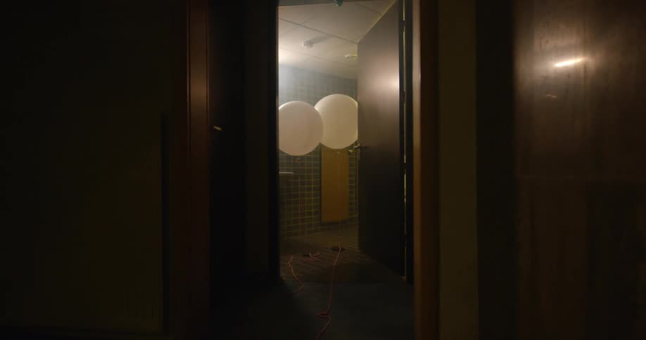 Camera moves down dark hallway to an open door showing a room with tile a light and a window