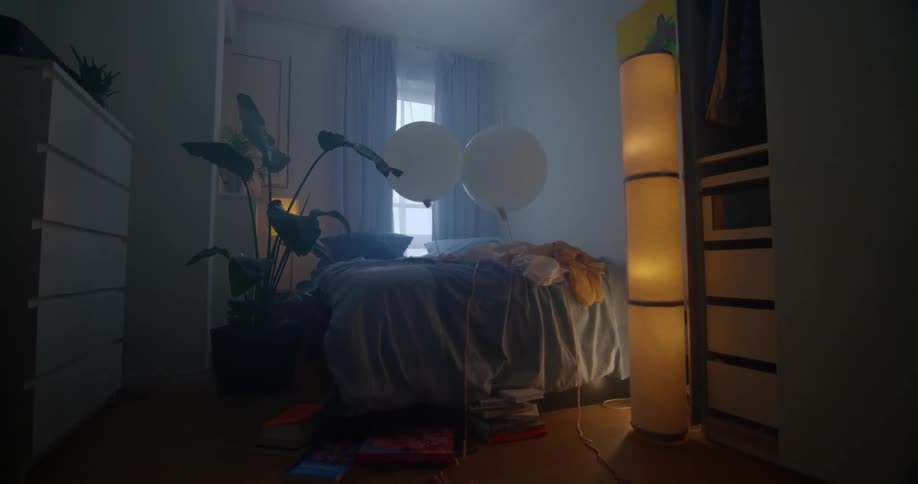 Empty bedroom with two white balloons on the bed in the middle