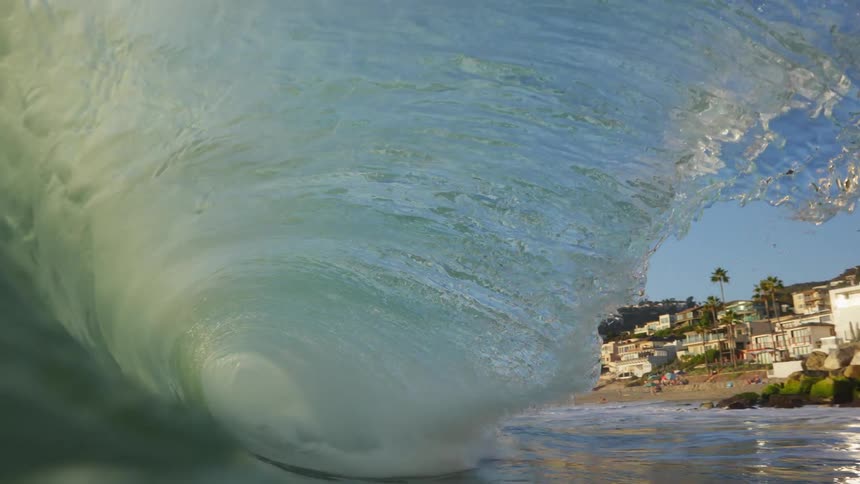 Sea wave breaks against the beach next to the coastal town