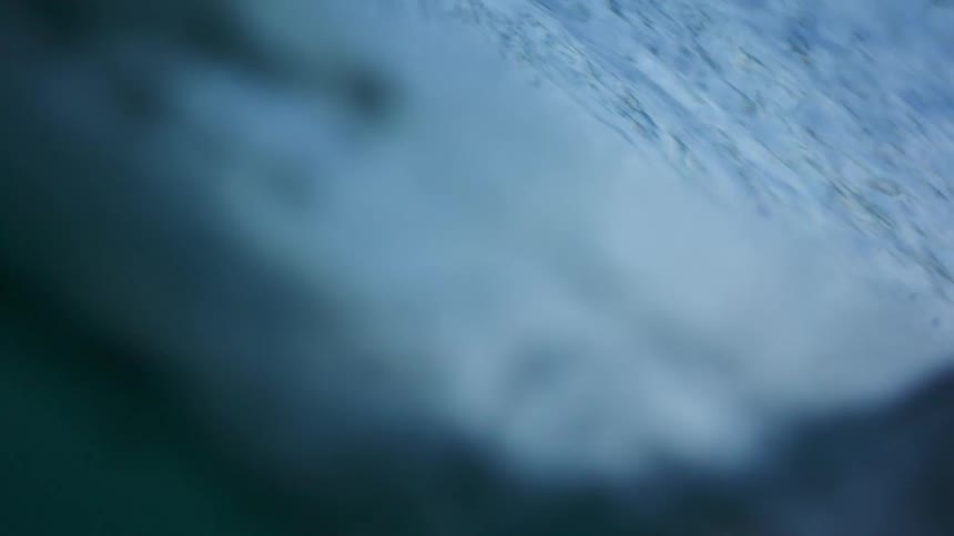 Ocean wave breaks against the beach at dusk