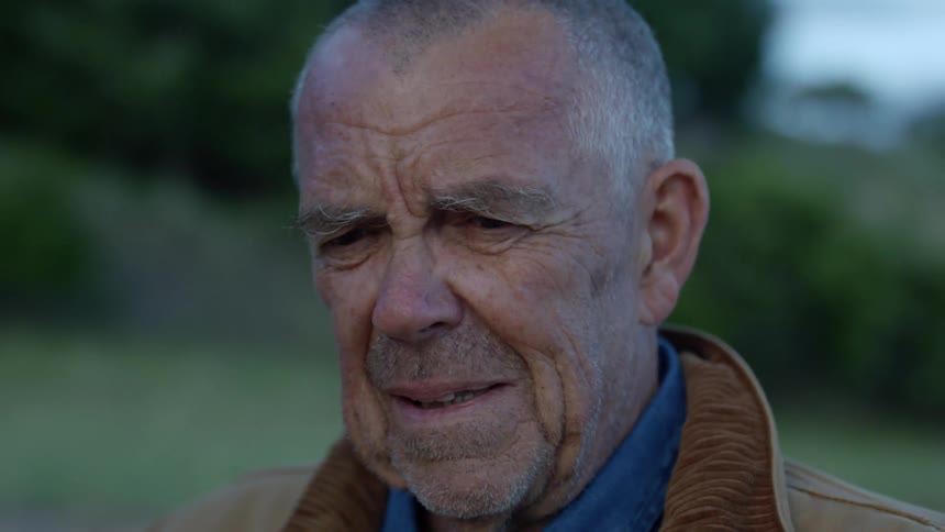An older white man stands outside with a worried expression