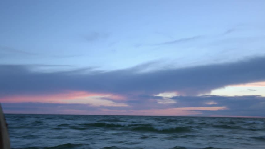 Man looks out over an ocean and looks up into the sky