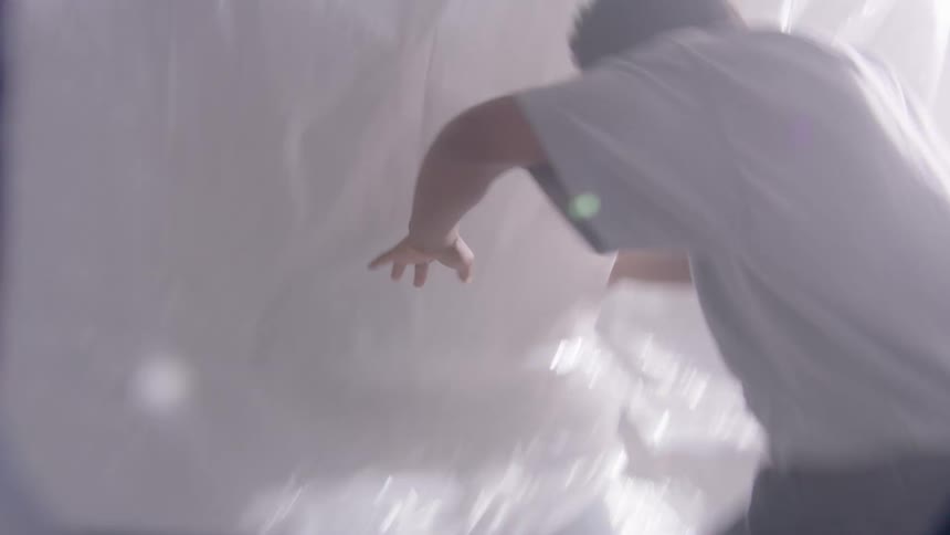 Man walking along plastic sheet covered hallway toward bright light begins staggering