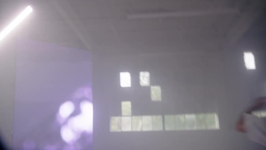 A young man dances frantically in a room with several flashing screens
