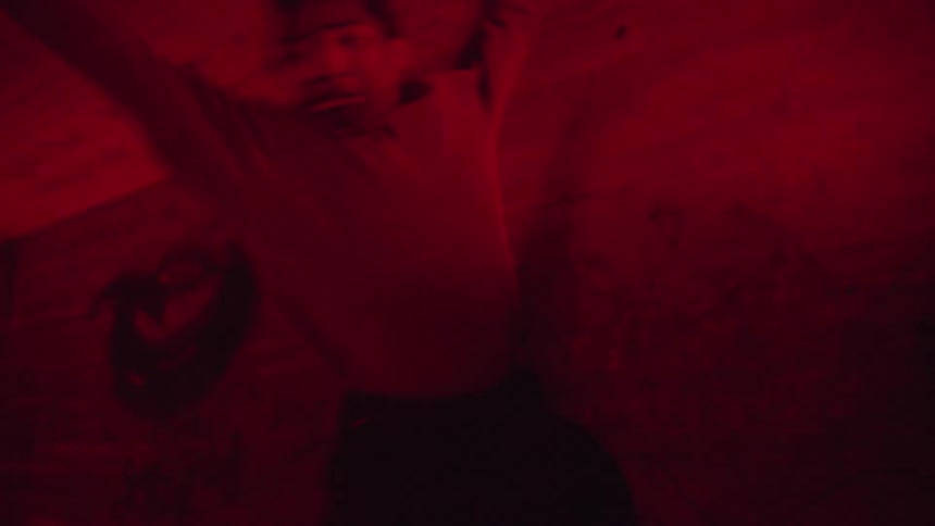 A black male dancing in a hallway with strobe red lights
