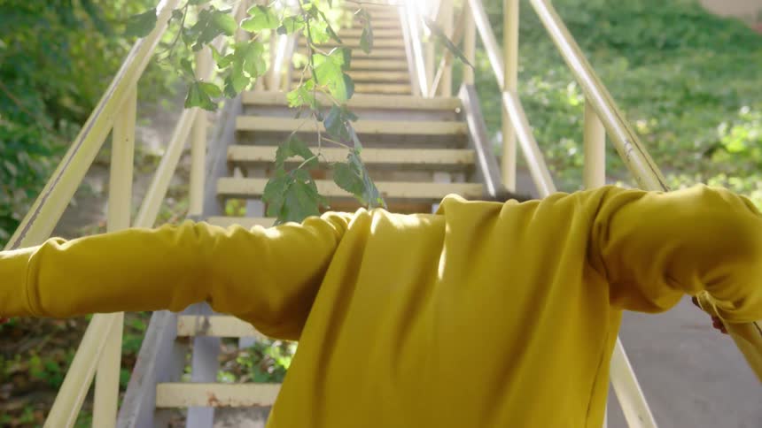 A person exits a tent and struggles to climb stairs to a platform for a train