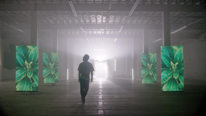 A man walks through a building with screens with photos flashing on them