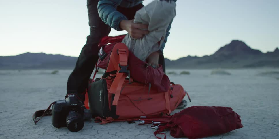 A man pulls out stakes and other tent gear from a backpack