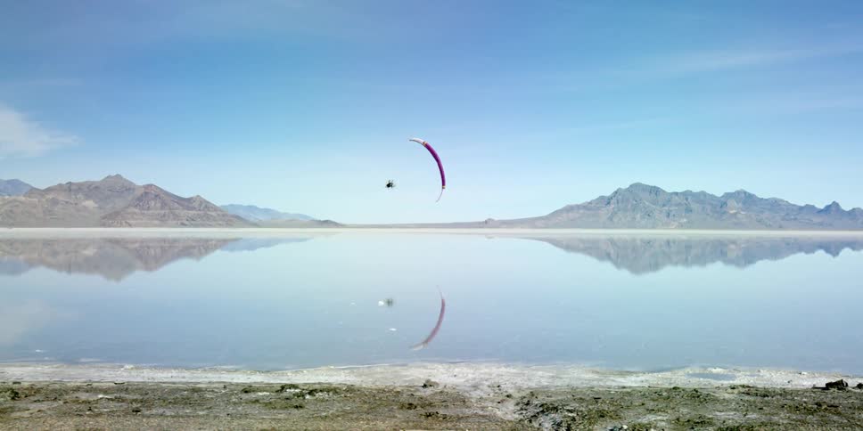 A person parachutes over a clear lake