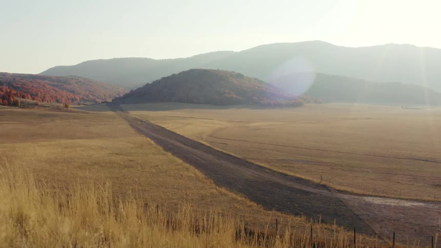 In a remote area a dirt road is carved through grassy plains