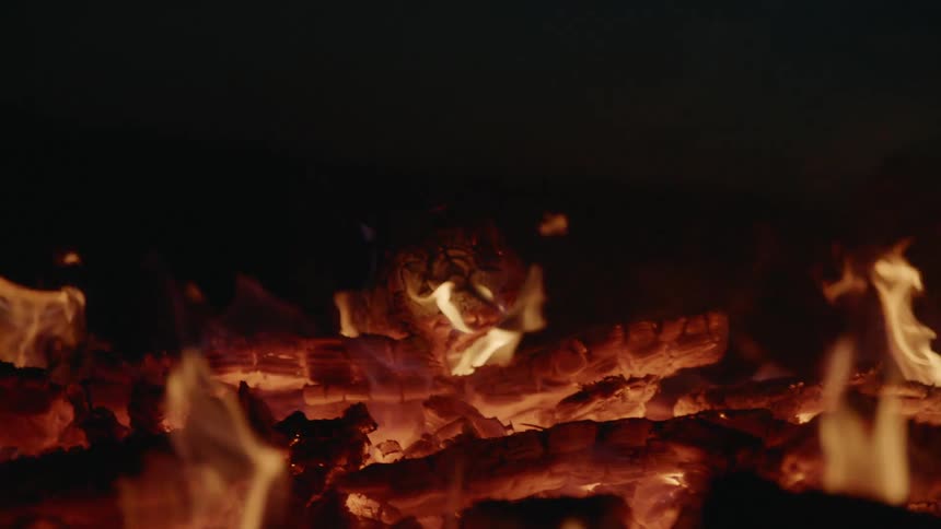 Stacks of wood burning outside in the dark