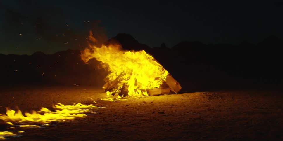 A trail of fire leads to a pile of burning logs