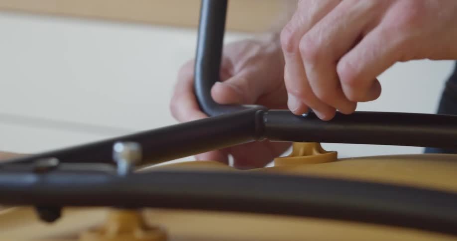 Hands are shown tightening a screw on a piece of furniture