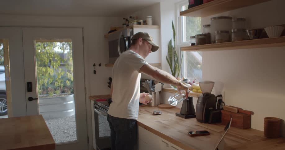 Man pouring water into a coffee maker in his kitchen at home during the day