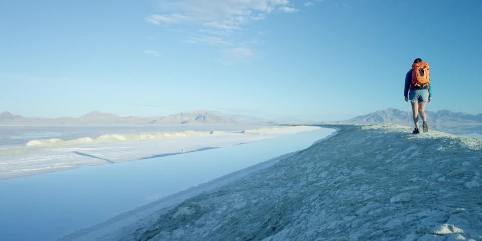 Woman with backpack hiking near a salt lake