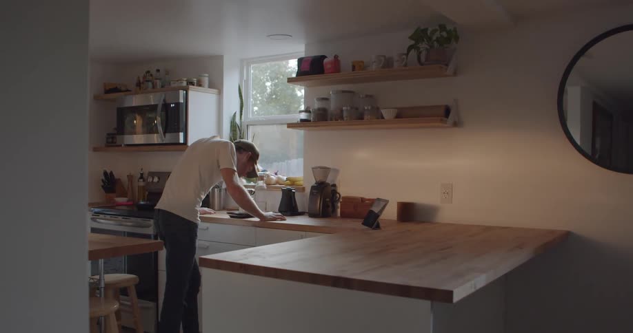 A man leans against the counter in his kitchen and puts his head down