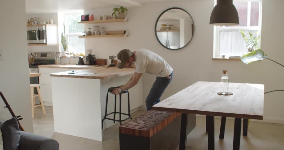 A caucasian male moving a stool in the kitchen