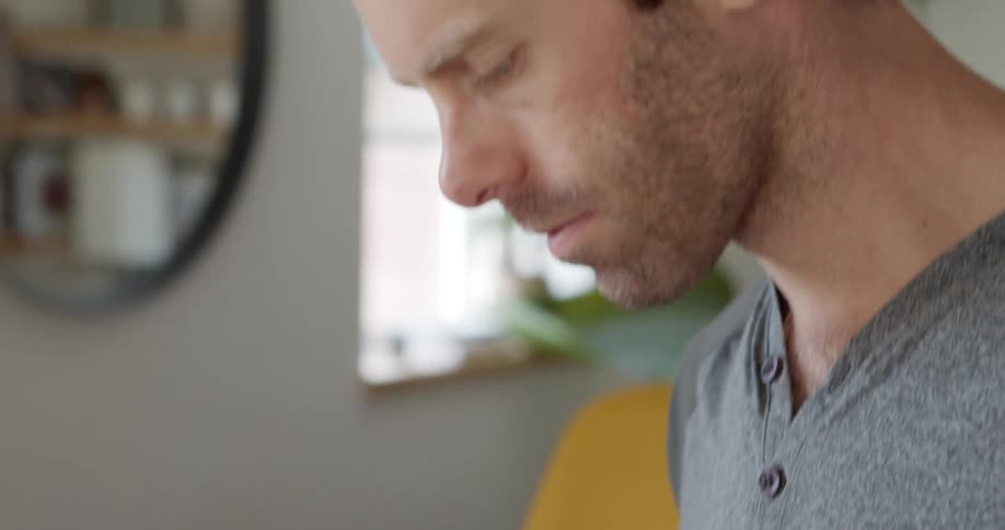 Man with a beard and a grey t shirt uses a tablet in the kitchen