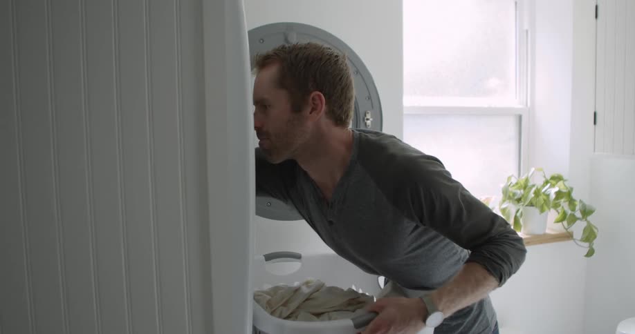 A man takes laundry out of a dryer at home