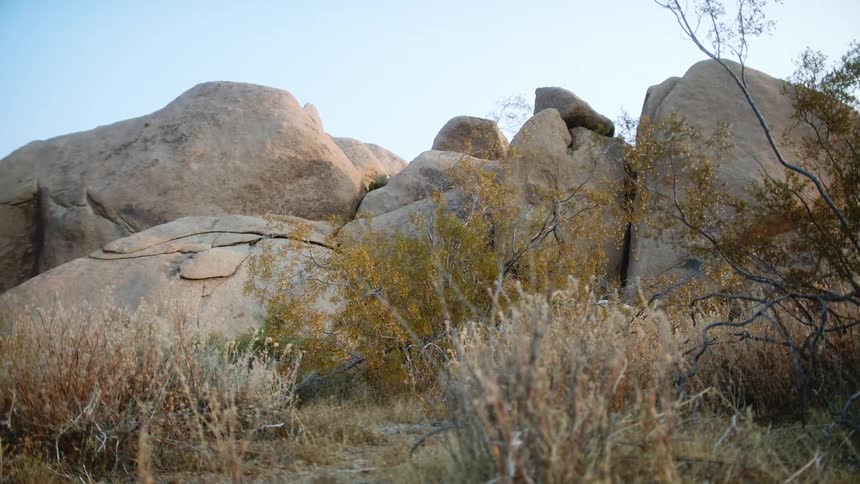 Pile of boulders some with cracks are surrounded by brown grass