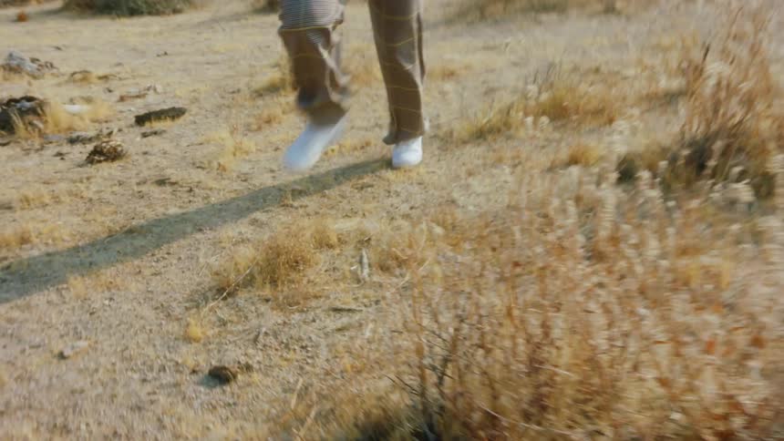 A woman laughs as she runs across soil