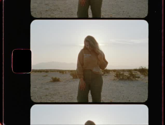 A woman with long hair stands in a desert posing for a picture