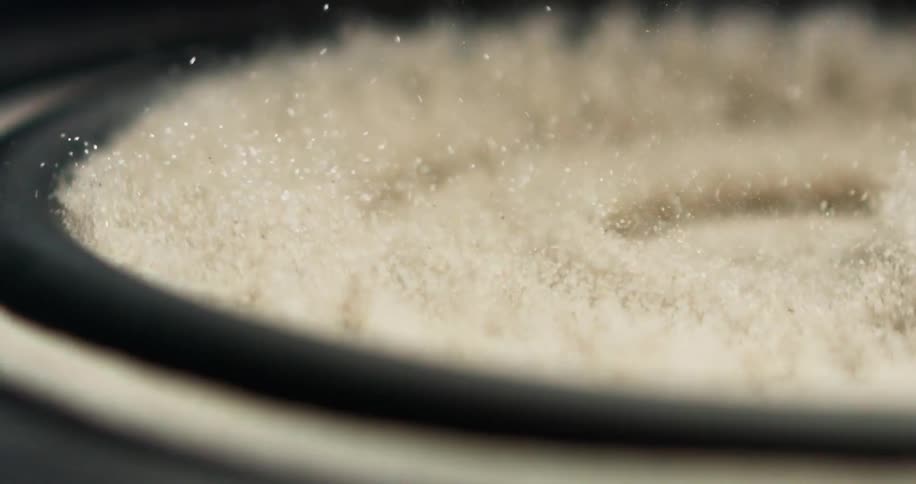 Beige sand rumbling around on top of a moving bass speaker