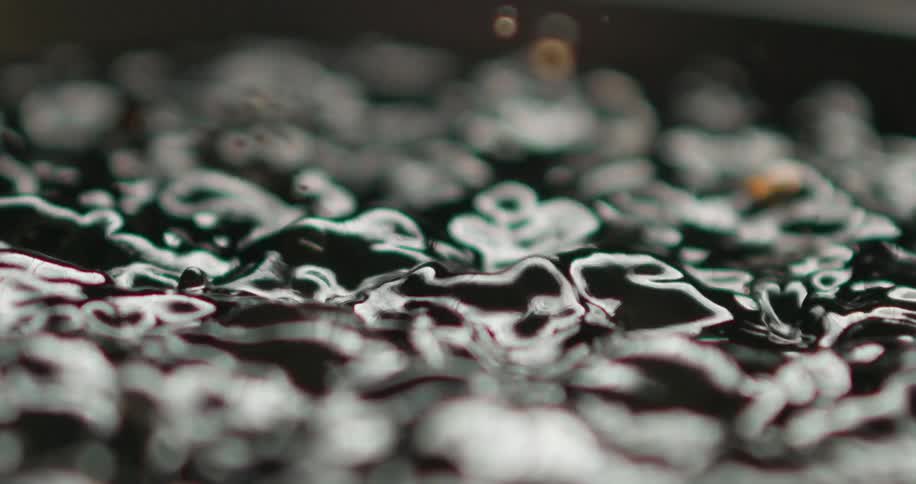 Liquid in a black setting is still and then moves quickly