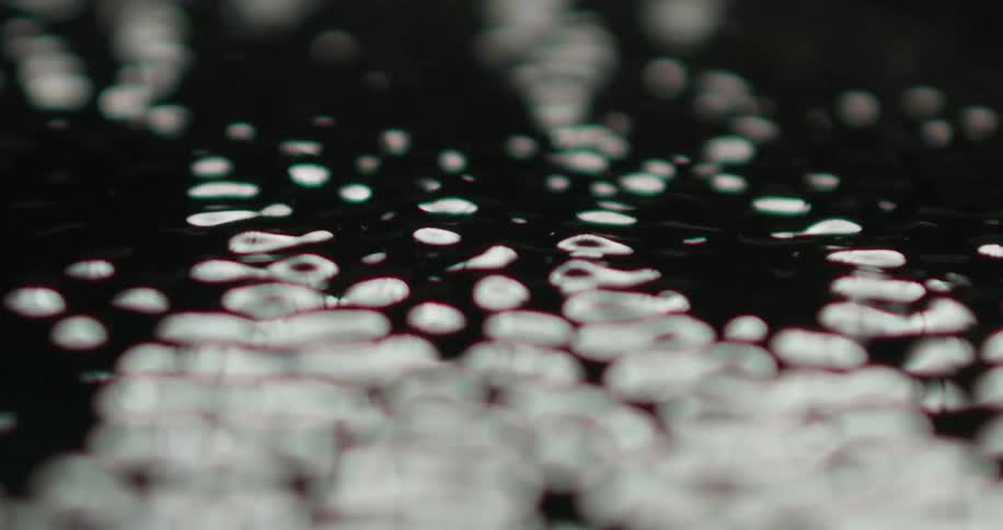 Dark liquid with light casted on top vibrating on a surface