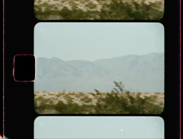 Mist obscures mountains on horizon as power lines cut through desert of scrub and sand