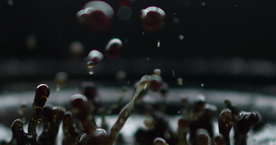 Dark brown liquid splashing around on top of a vibrating surface