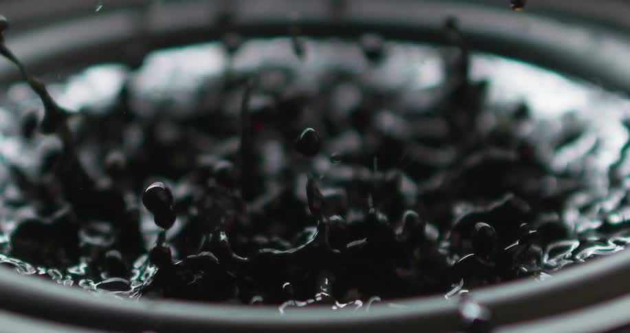 Black liquid builds up to a rapid boil splashing above the pot that it is in