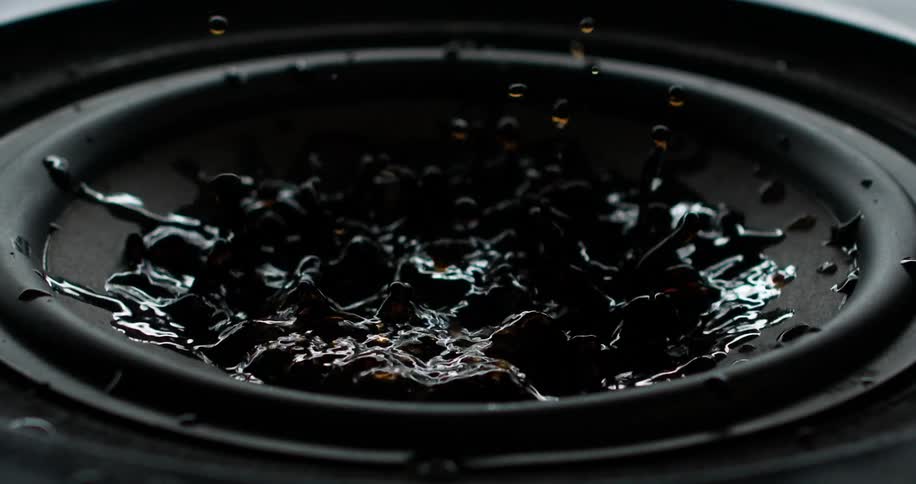 Bass speaker with brown liquid bouncing around on top as the speaker moves