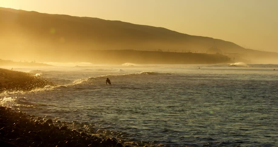 A person is in the ocean water at dusk