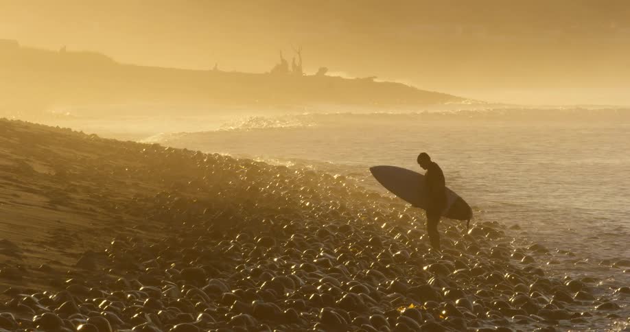 A person is walking on the beach at dusk
