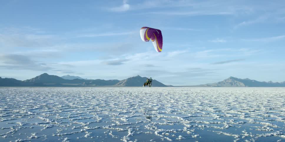A person is parasailing over ice covered water