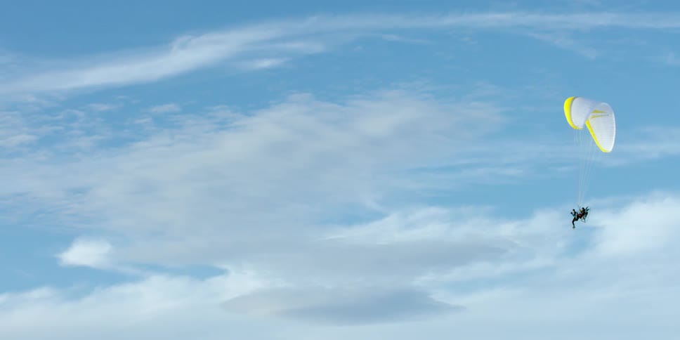 A person is parasailing through a cloudy sky