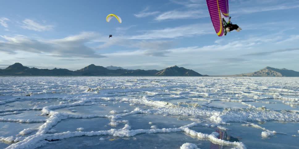 People are parasailing over ice covered water