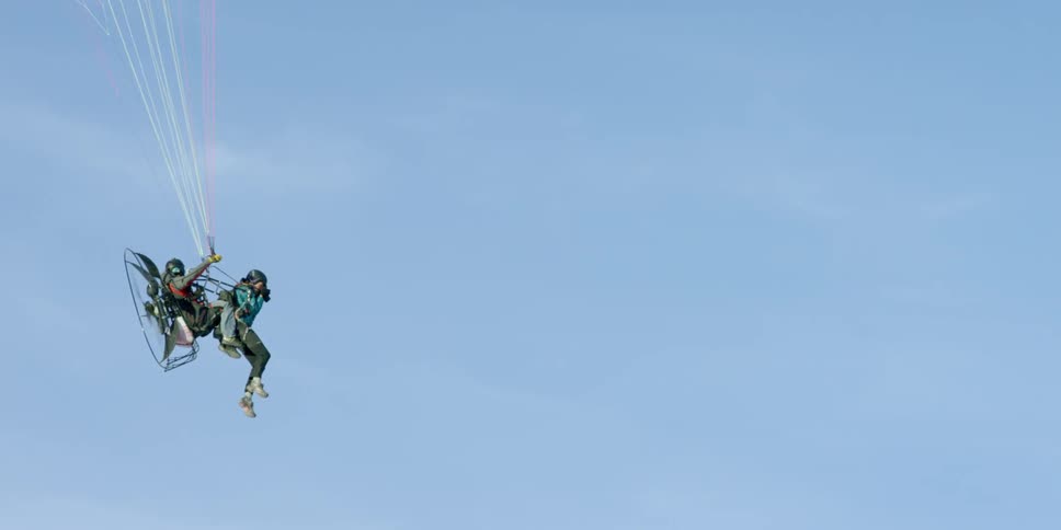 Two people parasailing with a paramotor