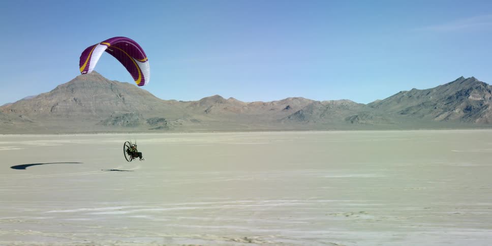 Person slowly ascending suspended from a parachute with a fan propelling them on their back