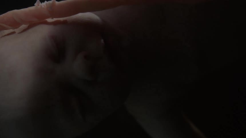 A baby is in utero floating as the baby is illuminated then darkness occurs
