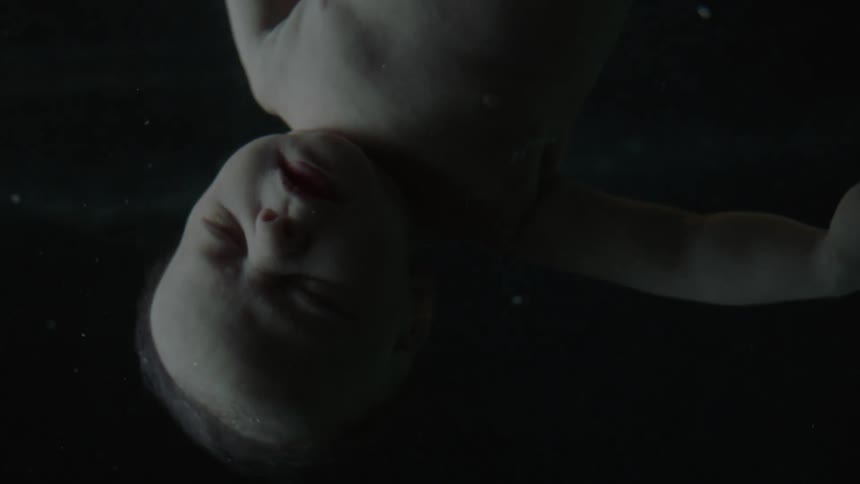A baby with white skin floats with a black background