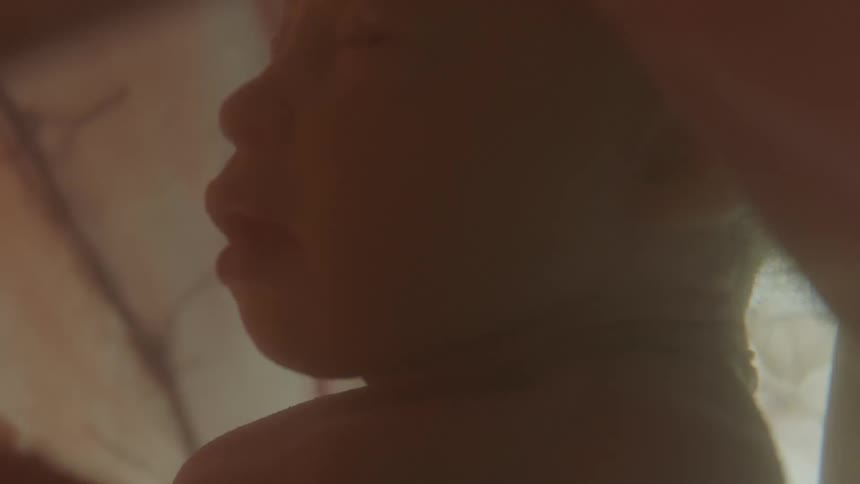 A baby floats in an amniotic sac with flashing lights in the background