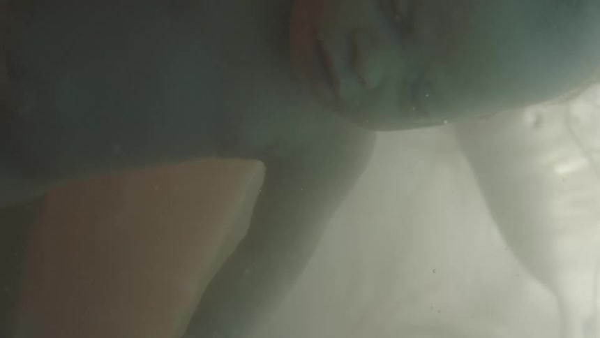 Unborn baby floats in gestational fluid back lit by light