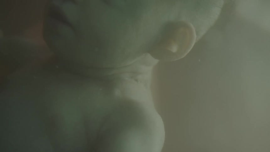 A baby floating in liquid with light strobing in and out