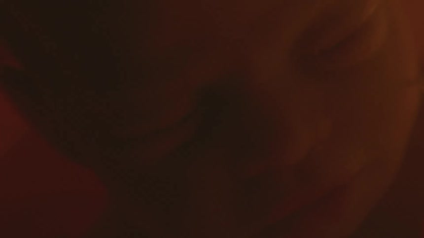 Baby sleeps while floating in orange tinted gestational fluid