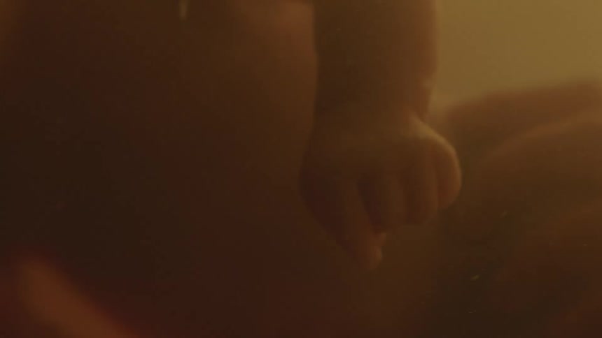 Unborn human baby floating in amniotic liquid inside the womb