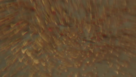 Clear liquid has tan metallic bubbles moving fast and then slow